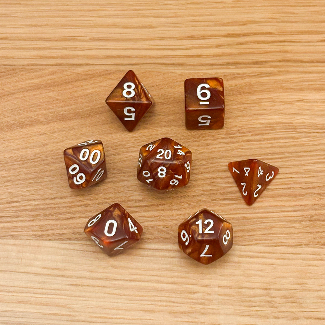 Set of 7 polyhedral dice (D4, D6, D8, D10, percentile D10, D12, D20) in swirled amber copper acrylic with white number infill.