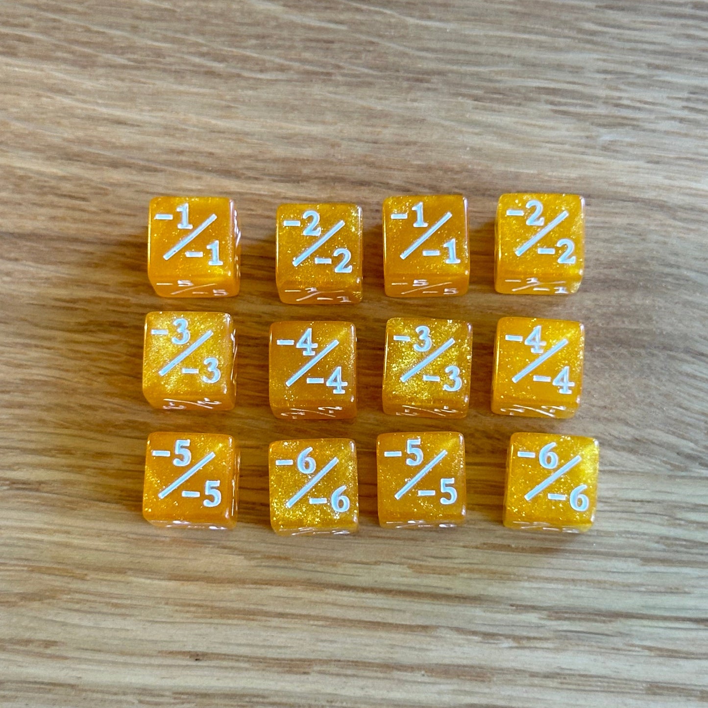 Set of twelve 12mm D6 -/ minus minus dice in glitter yellow with white infill. each dice is numbered 1-6 on each side to track incremental negative modifiers.
