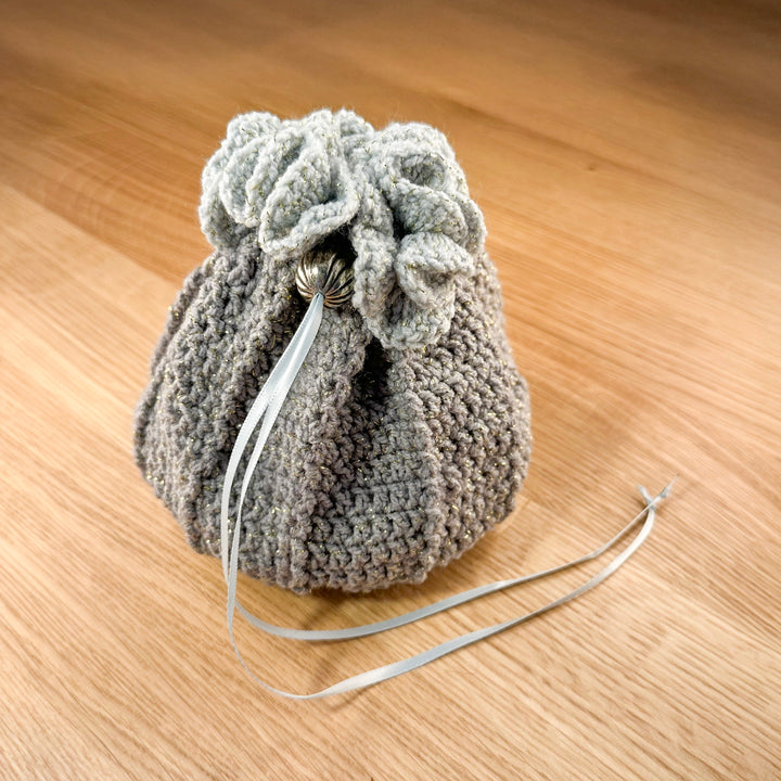 Closed grey and teal crochet dice bag with a silver bead closure. Part of the handmade hoard and fateweaver's collection.